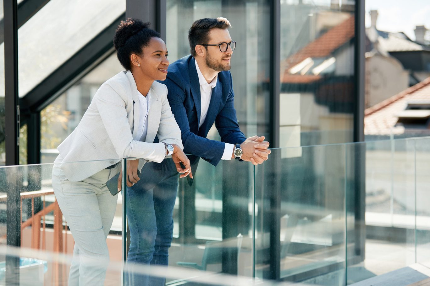 Happy African American businesswoman and her colleague enjoying during a break on balcony of an office building.